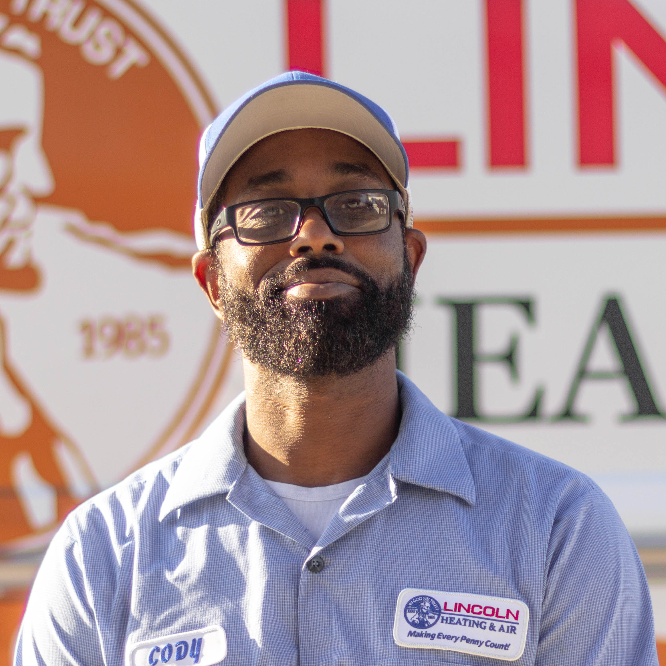 Cody T., installation technician at Lincoln Heating & Air, smiling in front of company vehicle with logo and slogan.