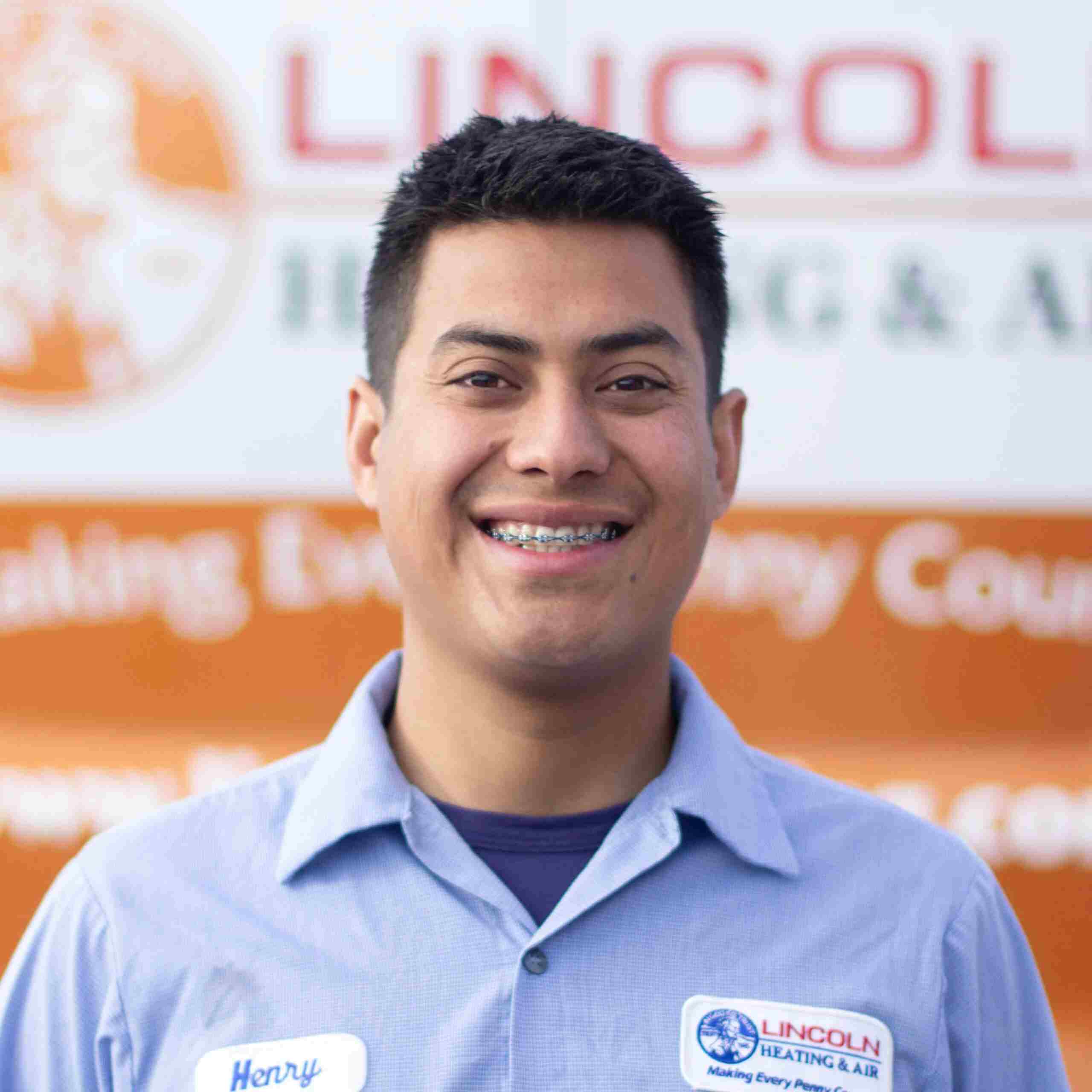 Henry T., Installation Field Supervisor at Lincoln Heating & Air, smiling in front of company logo and slogan, representing the family-oriented team culture and commitment to customer service.