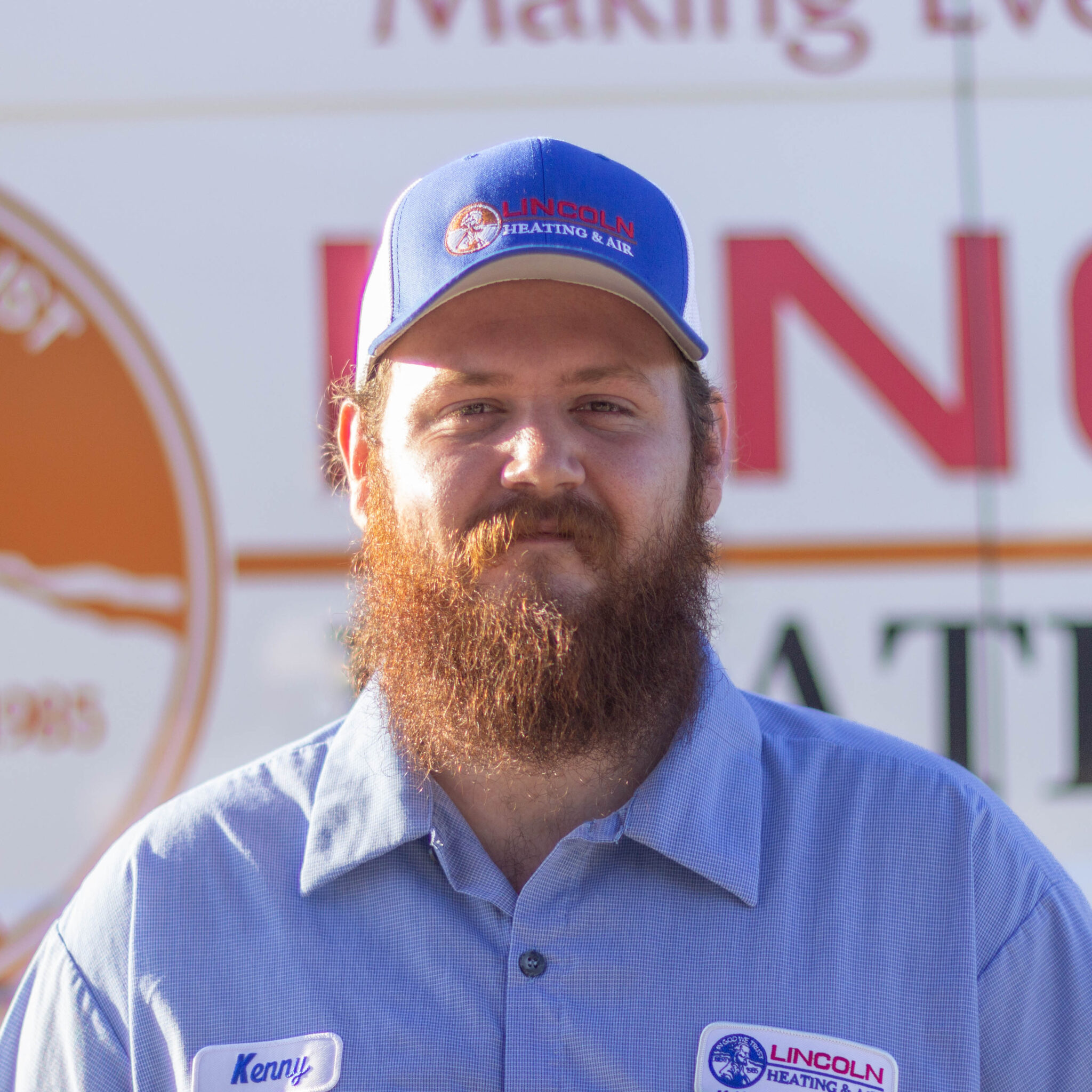 Kenny F., Warehouse Operator at Lincoln Heating & Air, wearing a blue cap and work shirt, with company logo visible in the background.
