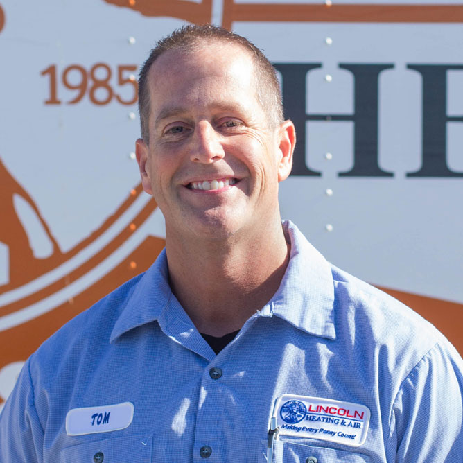 Tom C., estimator at Lincoln Heating & Air, smiling in front of company vehicle, showcasing team commitment to heating and cooling services.