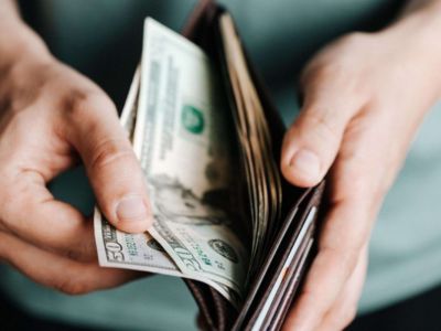 Person holding a wallet with cash, emphasizing financial savings from smart thermostat installation and energy-efficient HVAC solutions.