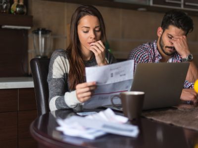 Couple reviewing high energy bills at home, expressing concern over heating costs, illustrating signs of a malfunctioning heater.