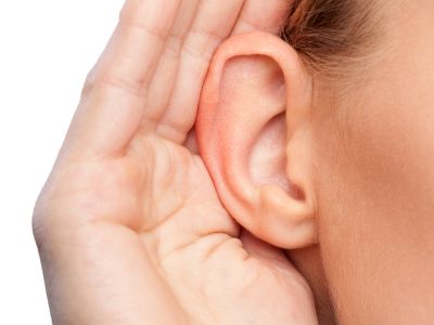 Person cupping hand to ear, symbolizing listening for unusual sounds from an air conditioning system, related to identifying refrigerant leaks.