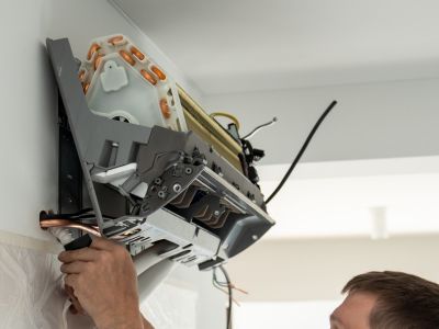 Technician installing a ductless mini-split air conditioning unit on a wall, showcasing the easy installation process and modern HVAC technology.
