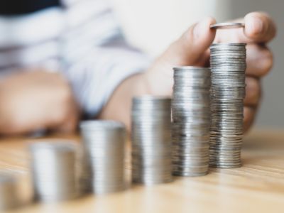 Hand stacking coins in ascending order, symbolizing savings and lower energy bills from ductless mini-split AC systems.