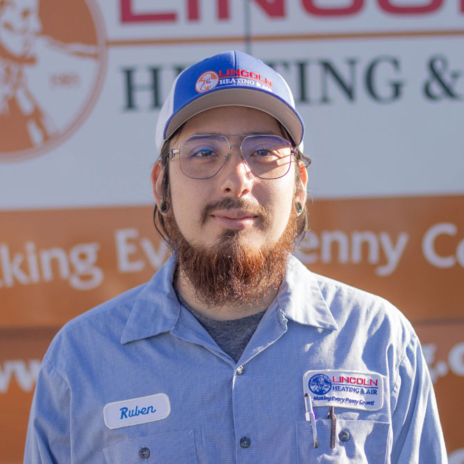Ruben C., Warehouse Operator at Lincoln Heating & Air, wearing company uniform and cap, standing in front of branded backdrop.