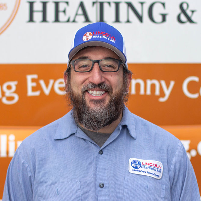 Mario G., Service Technician at Lincoln Heating & Air, smiling in front of company vehicle with logo and slogan.
